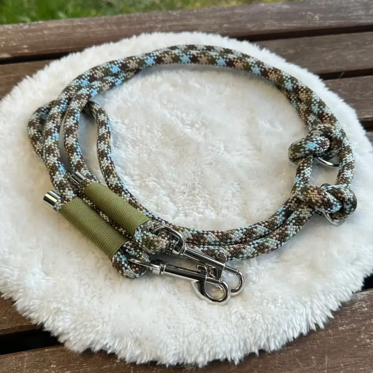 Eine Hundeleine aus einem Tau in Hellblau und Braun auf einem flauschigen, weißen Kissen.