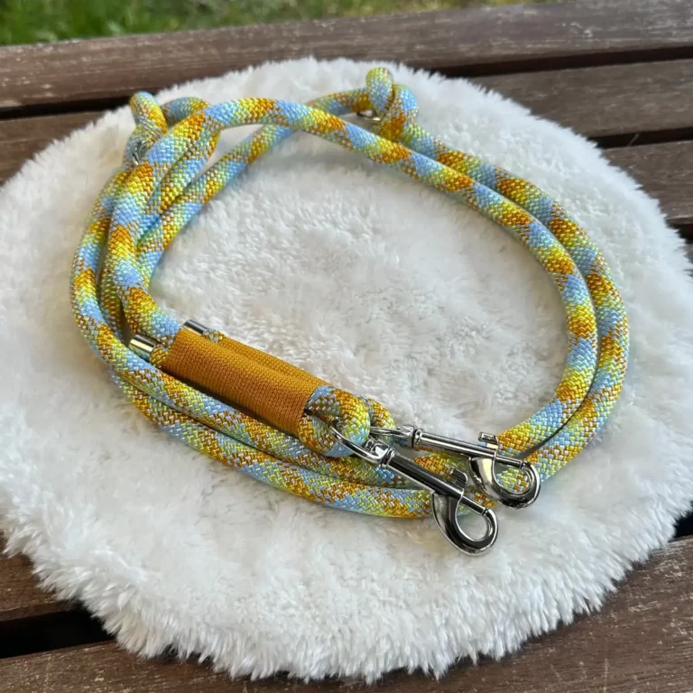 Eine Hundeleine aus einem Tau in Gelb und Blau auf einem flauschigen, weißen Kissen.